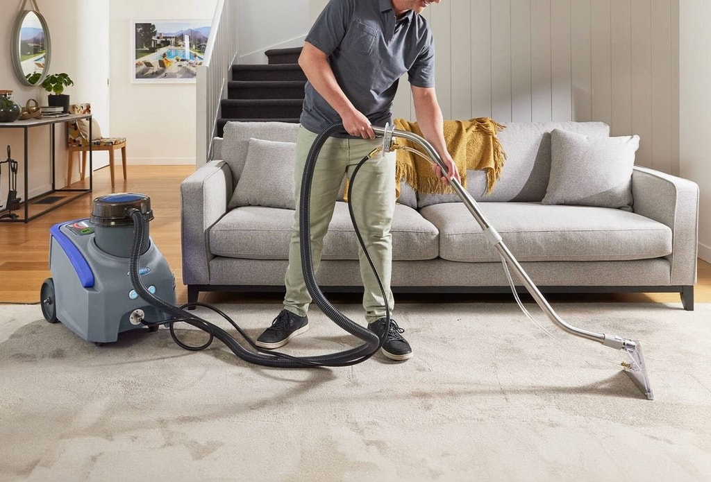 Technician performing bonnet cleaning service using low-moisture carpet machine in a residential living room.