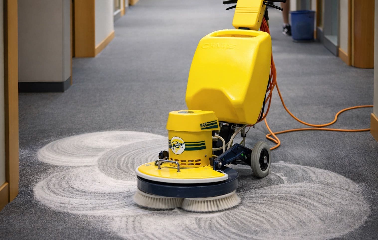 Professional carpet shampooing service using industrial rotary machine to deep clean commercial carpet with active foam extraction process.