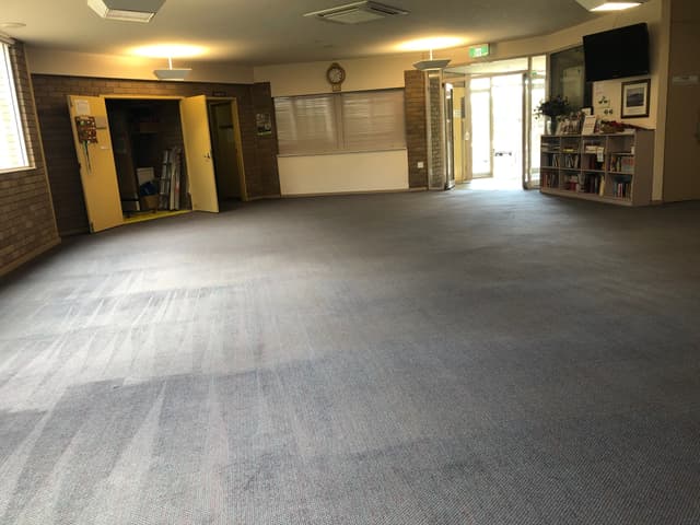 Large commercial hall carpet after professional steam cleaning, showing even cleaning lines and restored carpet fibres.