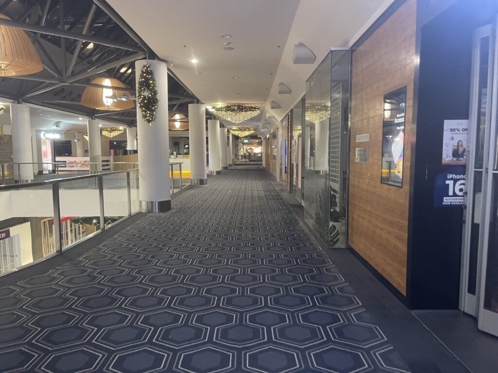 A professionally cleaned carpet in a shopping center hallway, maintaining a fresh and well-maintained commercial space.