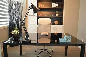 Clean and organized modern office with a desk, white chair, shelves, and decorative plants, showcasing professional office cleaning services.