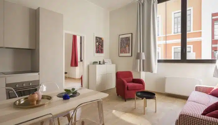 A bright, clean living room with a red armchair, modern decor, and a spotless carpet, showcasing the results of professional carpet steam cleaning for a fresh and inviting space.